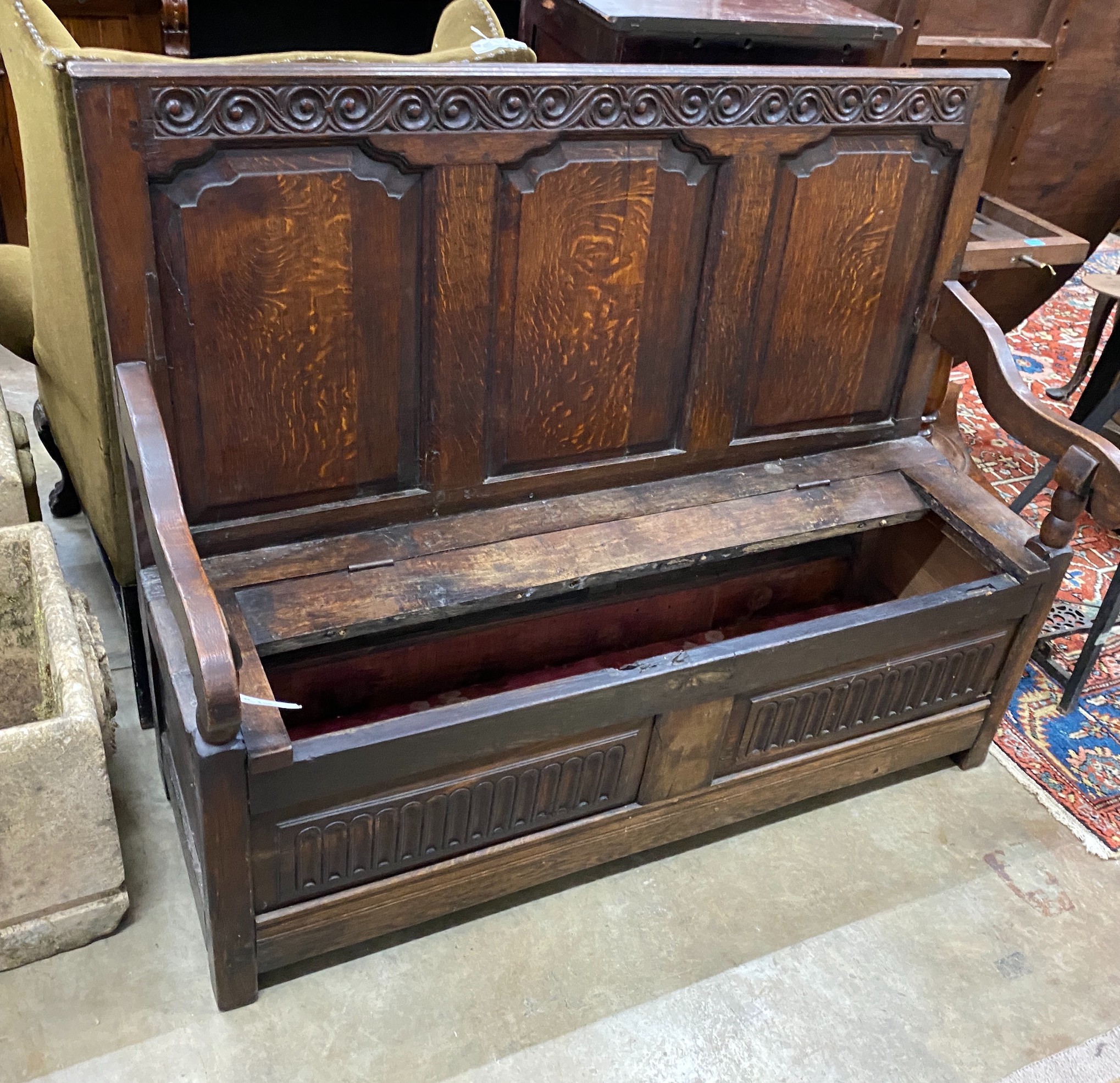 An 18th century carved panelled oak settle (seat in need of repair), width 136cm, depth 46cm, height 110cm